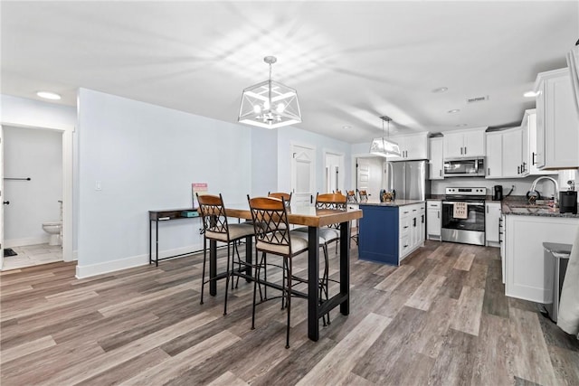 dining area featuring baseboards, visible vents, a notable chandelier, and light wood-type flooring