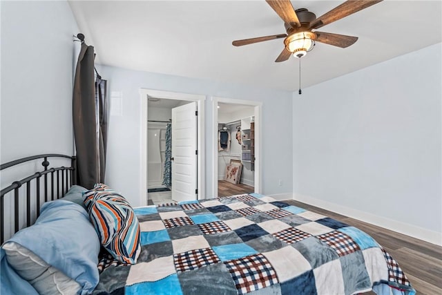 bedroom featuring connected bathroom, a ceiling fan, wood finished floors, a spacious closet, and baseboards