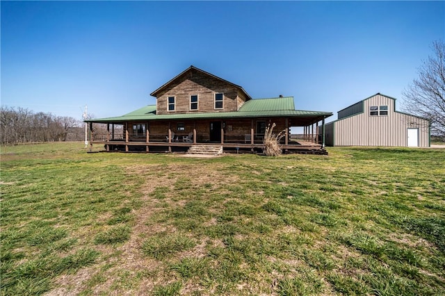 rear view of house featuring an outdoor structure, metal roof, a detached garage, covered porch, and a yard