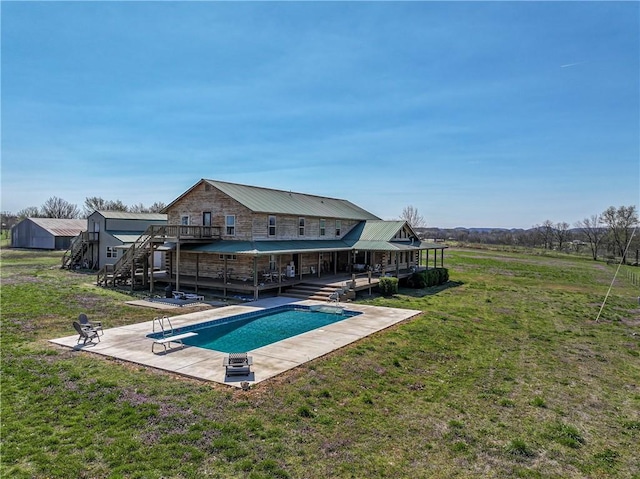 outdoor pool with stairs, a diving board, a deck, a patio, and a yard