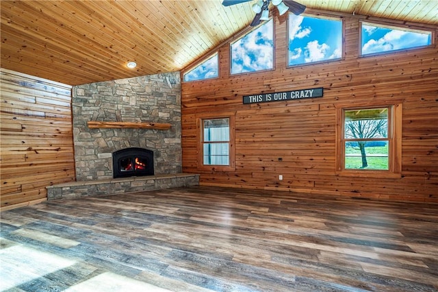 unfurnished living room featuring wooden walls, wooden ceiling, and a ceiling fan
