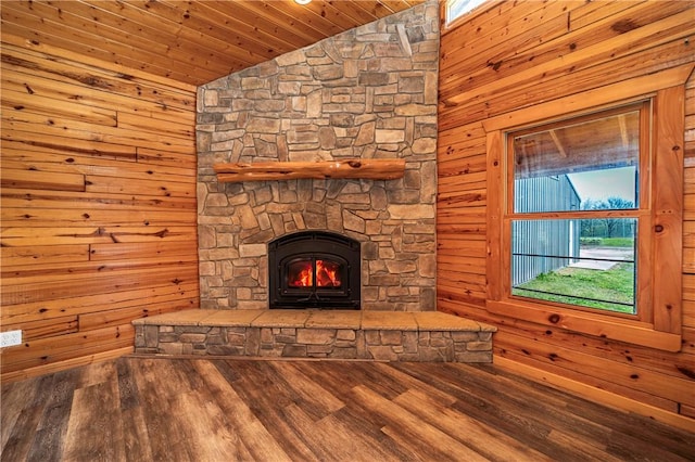 unfurnished living room with lofted ceiling, wood walls, and a stone fireplace