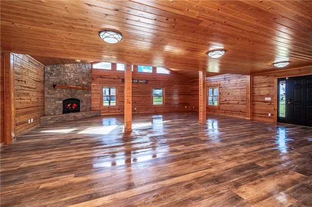 unfurnished living room with high vaulted ceiling, wooden ceiling, a fireplace, wood finished floors, and wood walls