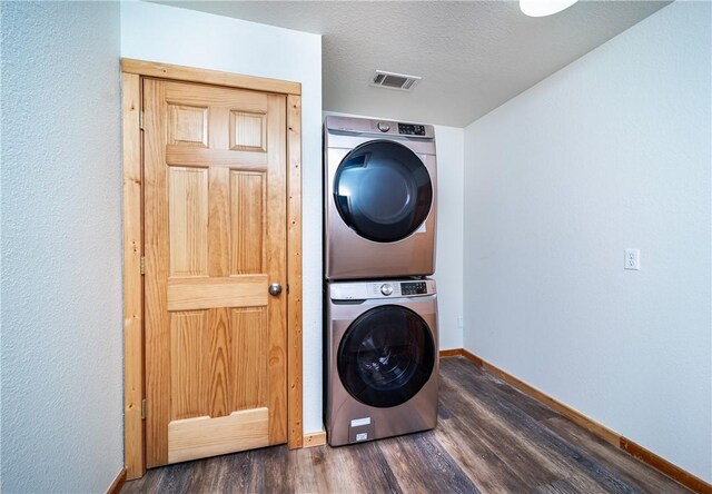 washroom with stacked washing maching and dryer, dark wood-style floors, laundry area, baseboards, and visible vents
