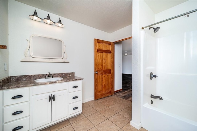bathroom with a textured ceiling, tile patterned floors, vanity, and washtub / shower combination