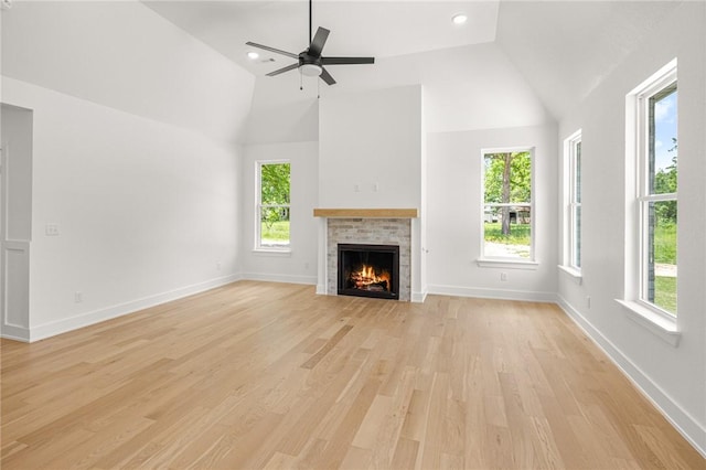 13040 Seba Rd, Centerton, AR 72719 - unfurnished living room featuring plenty of natural light, a lit fireplace, light wood finished floors, high vaulted ceiling, and recessed lighting