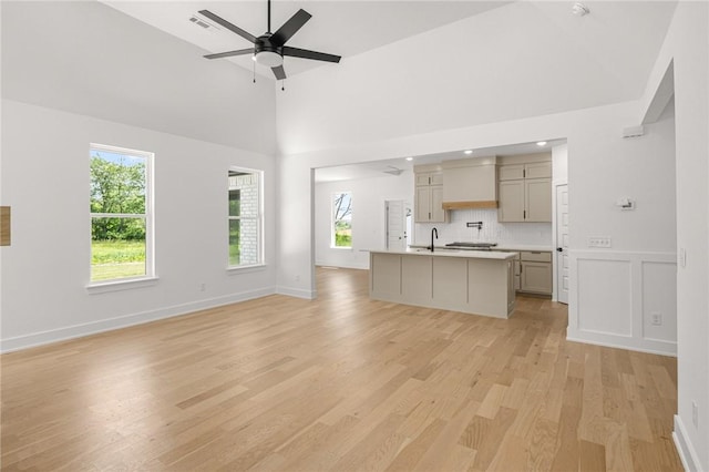 13040 Seba Rd, Centerton, AR 72719 - unfurnished living room featuring light wood-style flooring, ceiling fan, a sink, baseboards, and a high ceiling