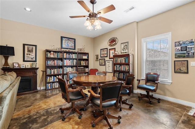 office space featuring visible vents, baseboards, concrete floors, a fireplace, and ceiling fan
