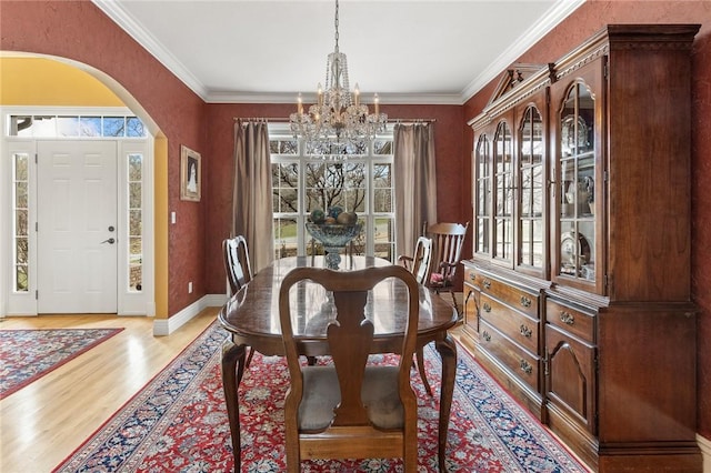 dining room featuring ornamental molding, arched walkways, a notable chandelier, and wood finished floors