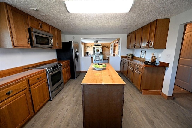 12766 Rocky Hill Rd, Prairie Grove, AR 72753 - kitchen featuring a kitchen island, butcher block countertops, appliances with stainless steel finishes, a textured ceiling, and light wood-style floors