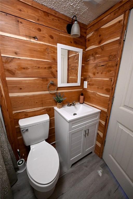 12766 Rocky Hill Rd, Prairie Grove, AR 72753 - bathroom featuring wood walls, toilet, vanity, and wood finished floors