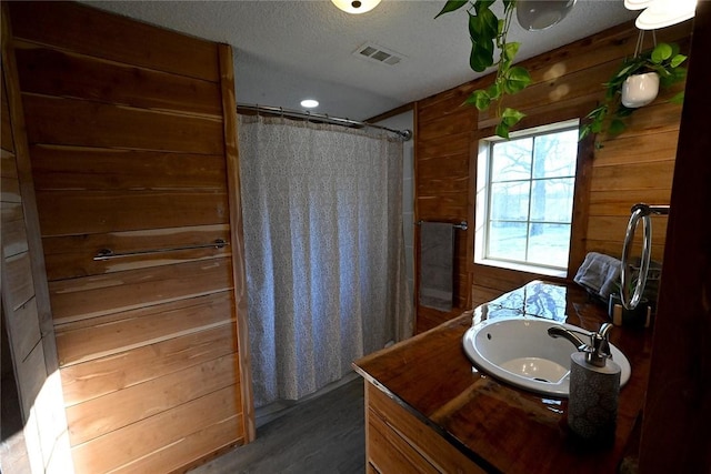 12766 Rocky Hill Rd, Prairie Grove, AR 72753 - full bath with a shower with curtain, vanity, wood walls, a textured ceiling, and visible vents