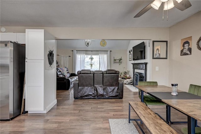 1801 Cash St, Neosho, MO 64850 - living room featuring light wood-style floors, a ceiling fan, and a fireplace with raised hearth