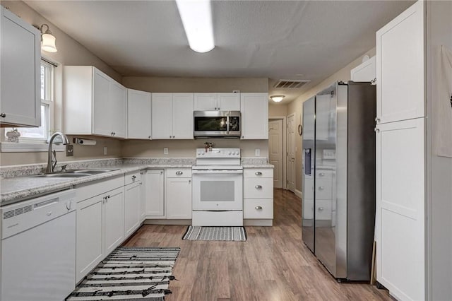 1801 Cash St, Neosho, MO 64850 - kitchen featuring light wood-style flooring, light countertops, visible vents, appliances with stainless steel finishes, and a sink