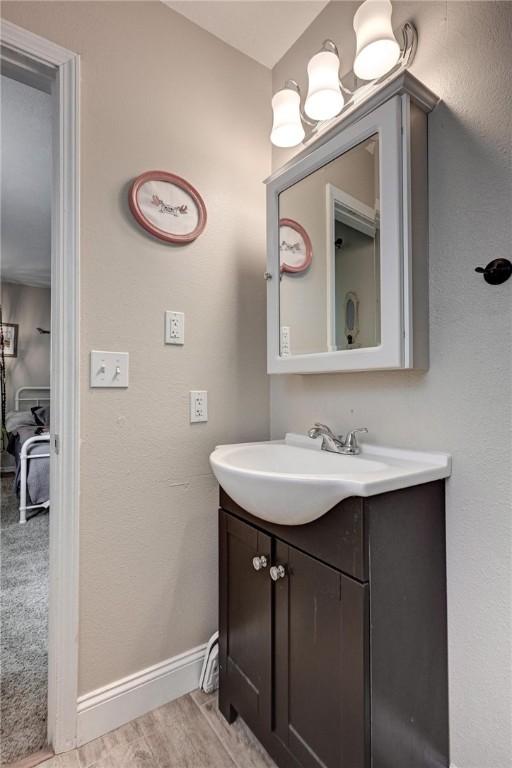 1801 Cash St, Neosho, MO 64850 - bathroom featuring baseboards, vanity, and wood finished floors