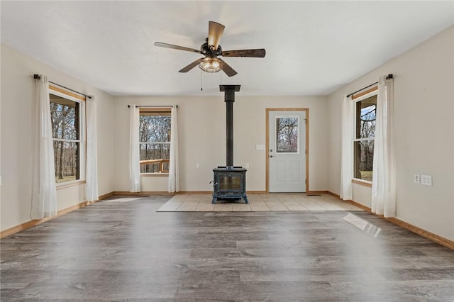1120 County Road 6012, Berryville, AR 72616 - unfurnished living room featuring a wealth of natural light, ceiling fan, wood finished floors, and a wood stove