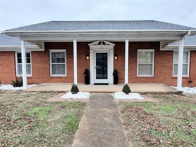 view of front of property with roof with shingles, covered porch, and brick siding