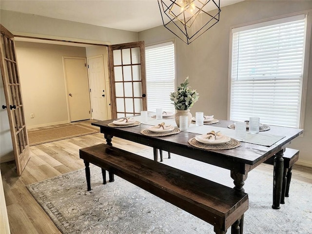 dining space with baseboards, light wood finished floors, and a notable chandelier