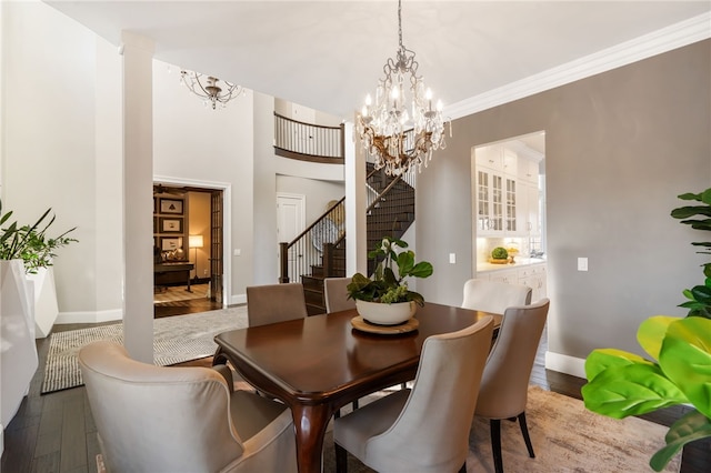 dining space with crown molding, wood finished floors, baseboards, a notable chandelier, and stairs