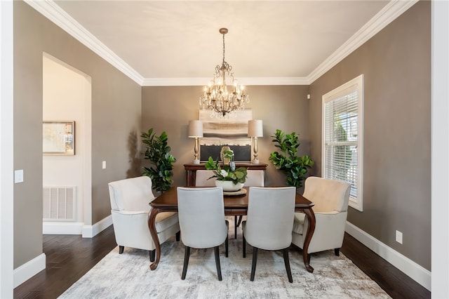 dining room featuring visible vents, ornamental molding, wood finished floors, baseboards, and a chandelier