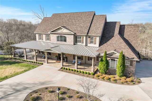 view of front of house featuring a standing seam roof, a shingled roof, a porch, and metal roof