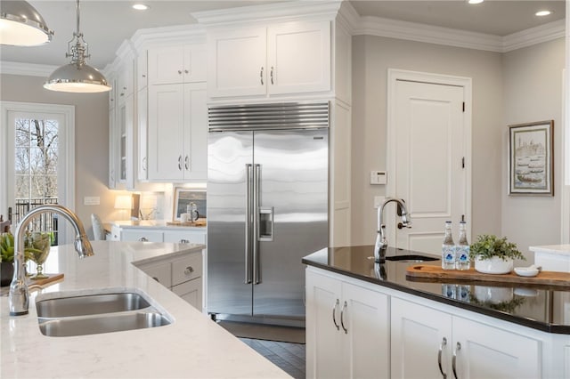 kitchen with a sink, white cabinets, and stainless steel built in refrigerator