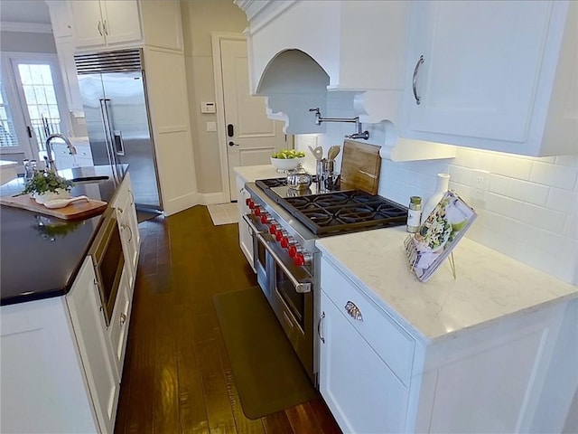 kitchen featuring a sink, dark wood finished floors, high quality appliances, and white cabinetry