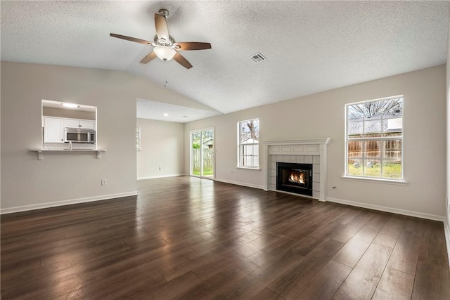 4292 W Beaver Ln, Fayetteville, AR 72704 - unfurnished living room with ceiling fan, lofted ceiling, dark wood-style flooring, a textured ceiling, and a tiled fireplace