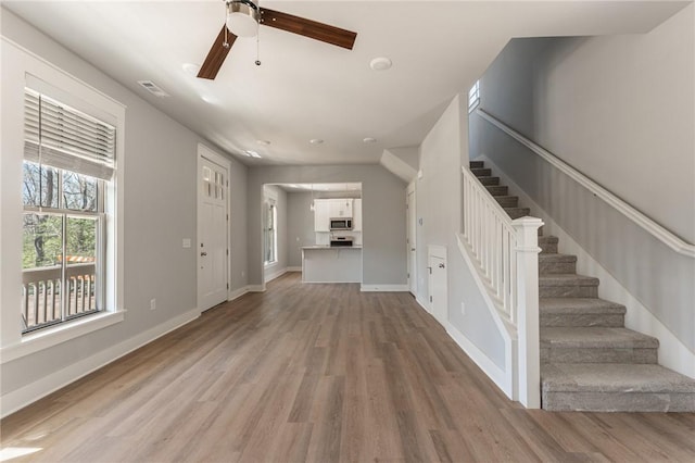 852 S Waxflower Ave, Fayetteville, AR 72701 - unfurnished living room with visible vents, light wood finished floors, baseboards, stairs, and a ceiling fan