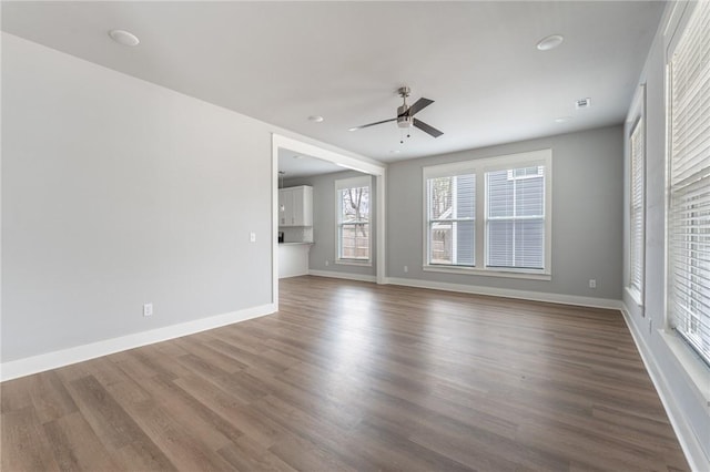 empty room with baseboards, visible vents, ceiling fan, and wood finished floors