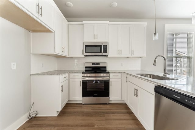 kitchen with dark wood finished floors, a sink, light stone counters, and appliances with stainless steel finishes