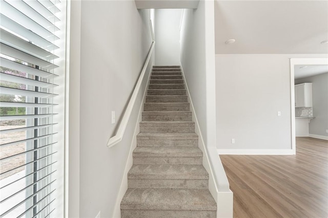 staircase featuring baseboards and wood finished floors