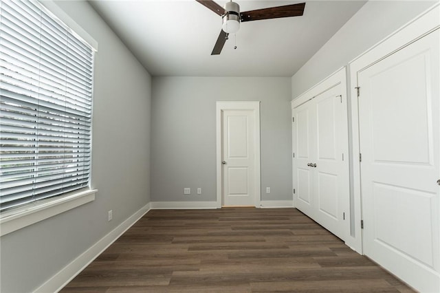 unfurnished bedroom featuring dark wood-type flooring, ceiling fan, and baseboards