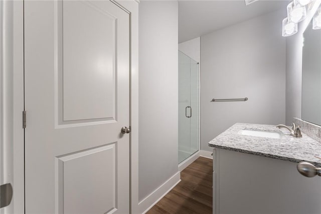 bathroom featuring vanity, a shower stall, baseboards, and wood finished floors