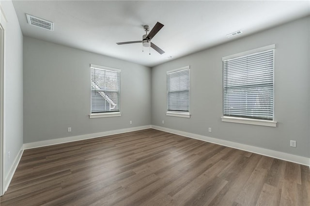 unfurnished room featuring ceiling fan, visible vents, and dark wood finished floors