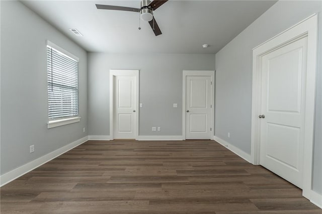 unfurnished bedroom featuring baseboards, visible vents, dark wood-type flooring, and a ceiling fan
