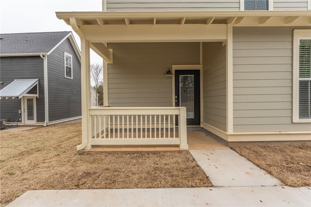 entrance to property with a lawn, covered porch, and central AC