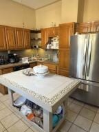 805 N Front St, Dardanelle, AR 72834 - kitchen featuring freestanding refrigerator, light countertops, light tile patterned floors, and brown cabinetry