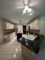 604 S Seattle Ave, Russellville, AR 72801 - kitchen with dark countertops, a peninsula, light tile patterned flooring, and ceiling fan