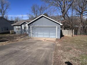ranch-style house with a garage, driveway, and fence
