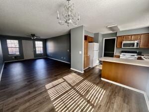kitchen with stainless steel microwave, dark wood-style flooring, open floor plan, light countertops, and brown cabinets