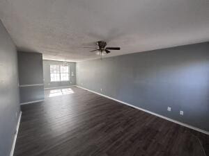 spare room featuring dark wood-type flooring, ceiling fan, and baseboards