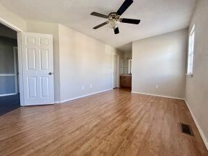 interior space with visible vents, ceiling fan, wood finished floors, and baseboards