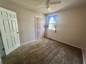 unfurnished bedroom with carpet floors, baseboards, a closet, and a textured ceiling
