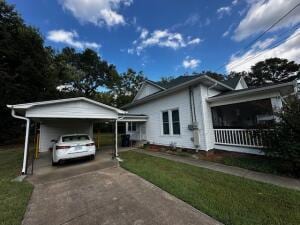 view of front facade with a carport, concrete driveway, and a front lawn