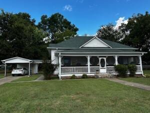 view of front facade featuring a front yard, a porch, a carport, and driveway