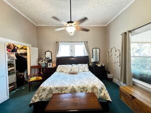 bedroom featuring dark carpet, a textured ceiling, and ornamental molding