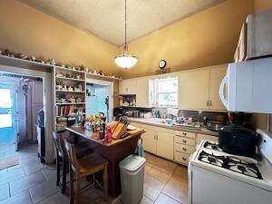 kitchen featuring white cabinets, decorative light fixtures, light countertops, white appliances, and vaulted ceiling