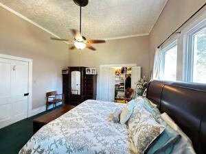 bedroom featuring a textured ceiling, ornamental molding, and ceiling fan