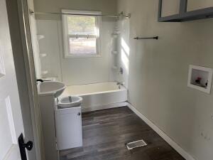 full bathroom featuring baseboards, wood finished floors, vanity, and shower / washtub combination
